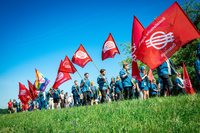 junge Menschen gehen im traditionellen SJ-Blauhemd gekleidet mit roten SJ-Fahnen