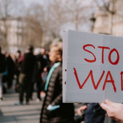 Demonstrierender mit einem Schild mit der Aufschrift "Stop War"